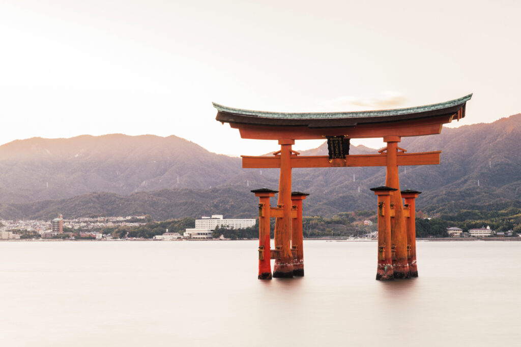 The Itsukushima Shrine in a lake surrounded by hills covered in greenery in Japan